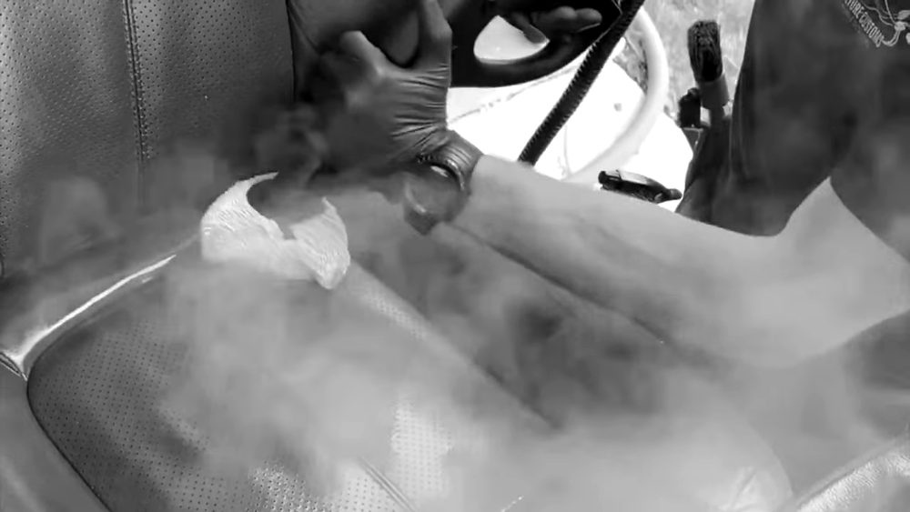 Steam cleaning a leather seat during an interior detail
